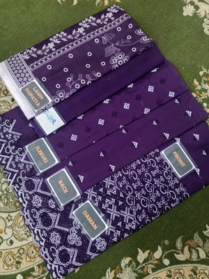 Purple fabric with white patterns and brand labels on a green patterned surface