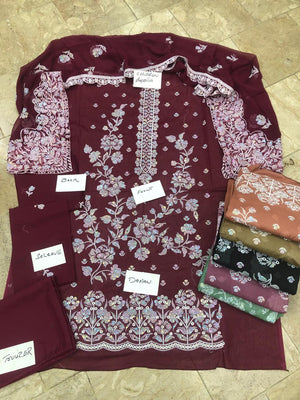 Maroon fabric with floral patterns and labels on a tiled floor