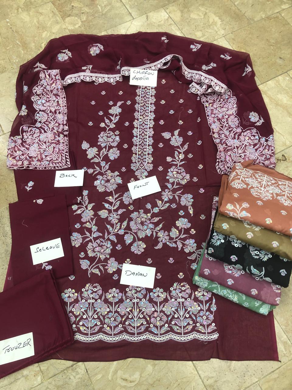 Maroon fabric with floral patterns and labels on a tiled floor