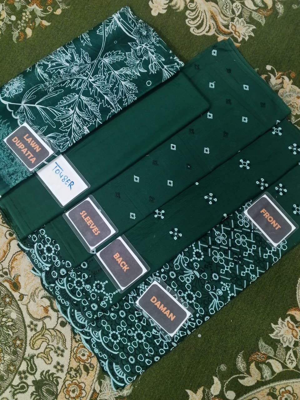 Set of green fabric swatches with labels on a patterned fabric background