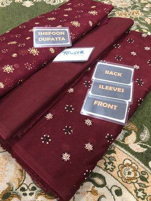 Maroon dupatta with gold patterns on a patterned fabric background